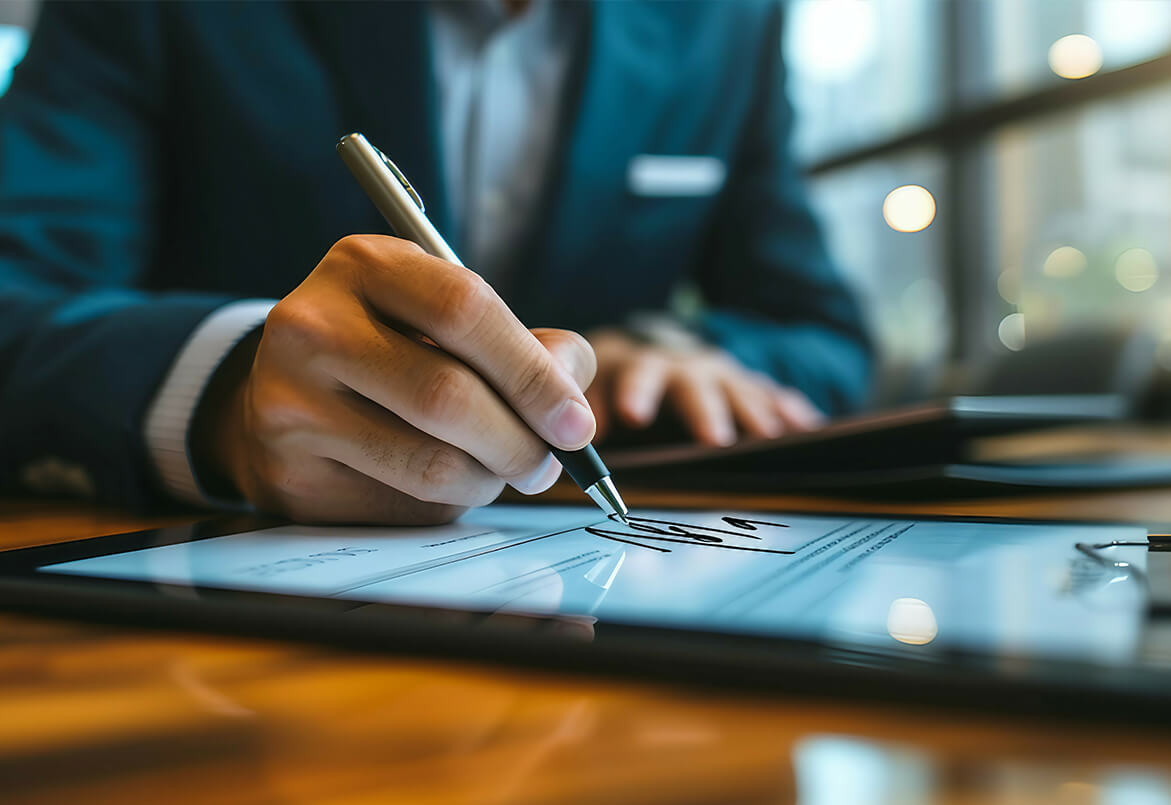 Person signing a digital document on a tablet with a stylus in a modern office setting.